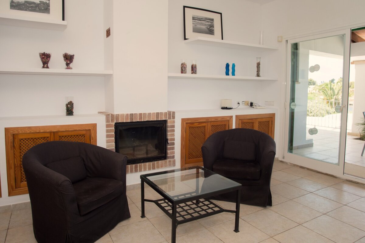 A living room with two black chairs and a fireplace