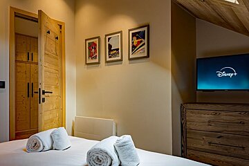 A bedroom with a flat screen tv that says disney +