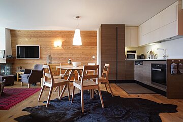 A kitchen with a table and chairs and a rug on the floor