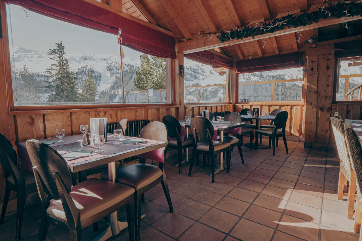 A restaurant with tables and chairs and a view of the mountains