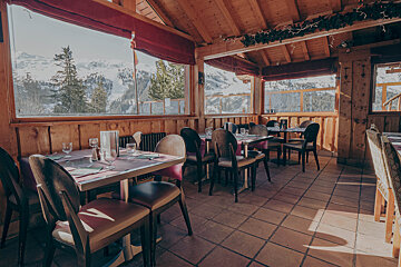 A restaurant with tables and chairs and a view of the mountains