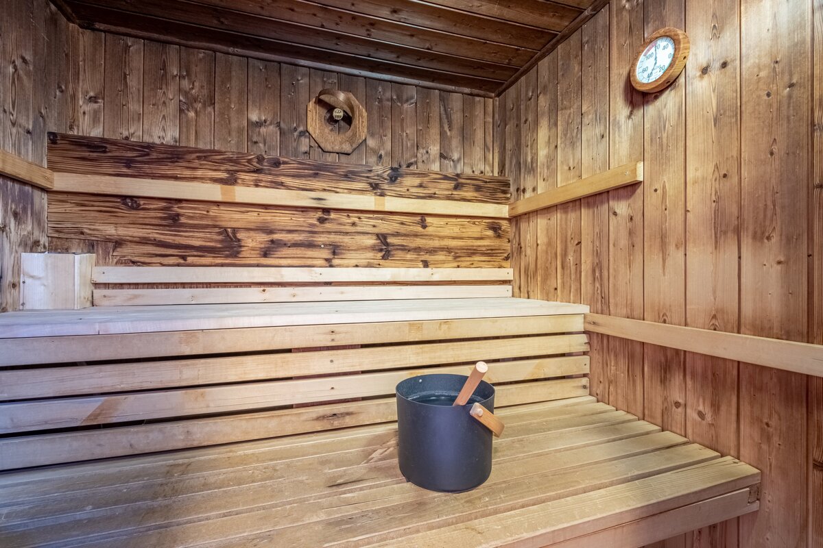 A wooden sauna with a bucket and a clock on the wall