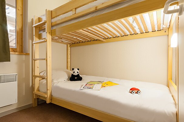A bunk bed with a teddy bear and a book on it