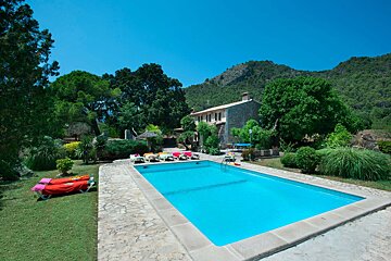 A large swimming pool with a house in the background