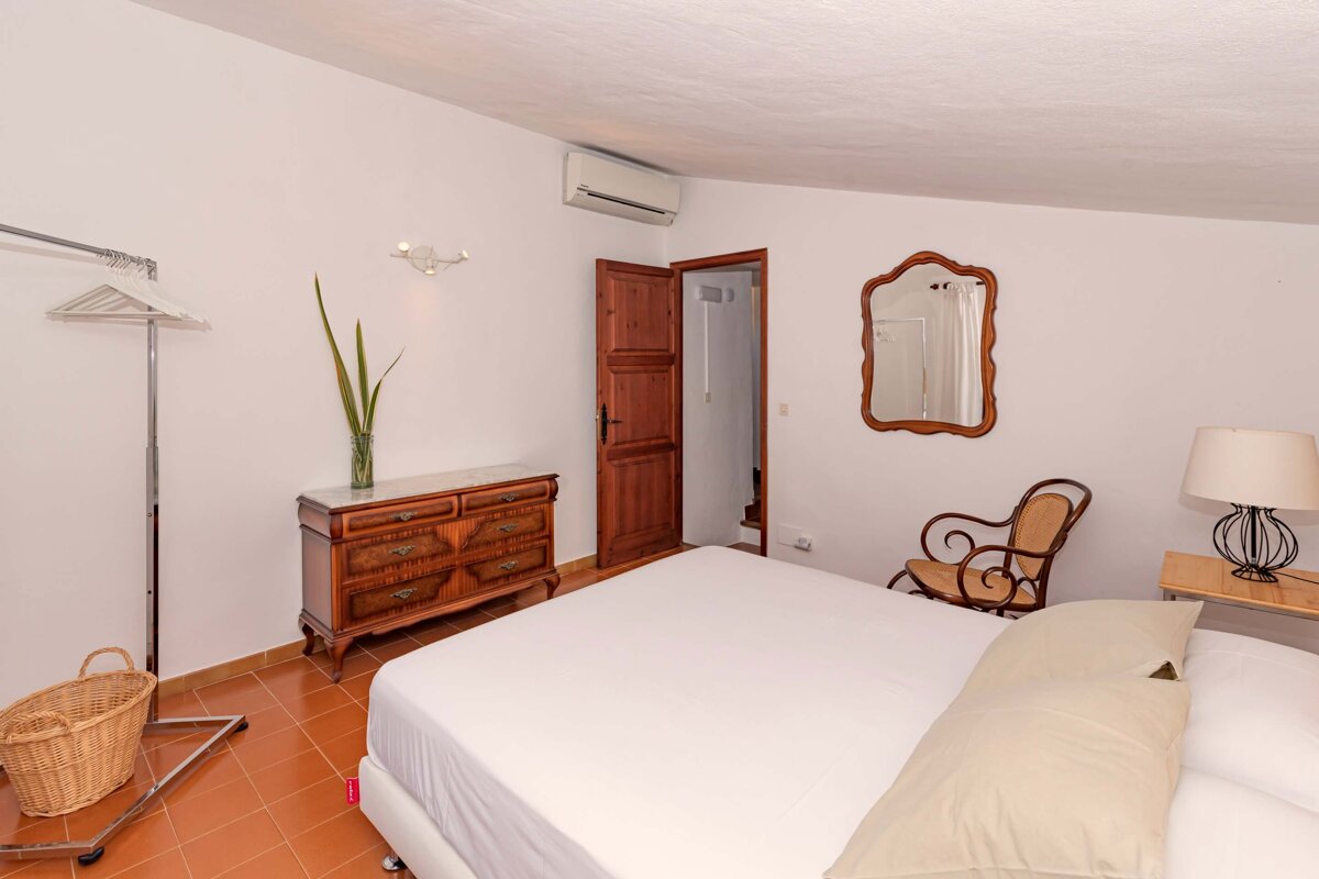 A bedroom with a large bed a dresser and a mirror