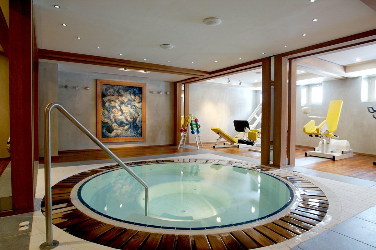A jacuzzi in a gym with a painting on the wall above it