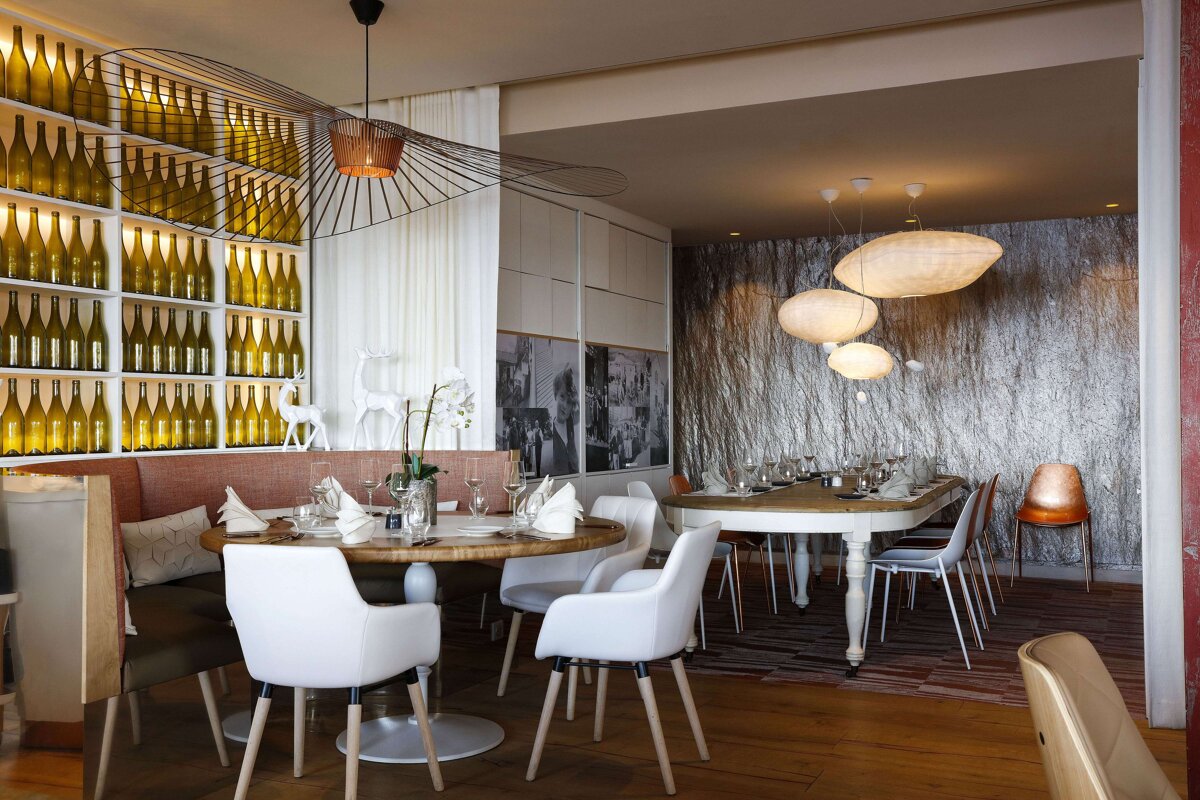 A dining room with a table and chairs and bottles on the wall