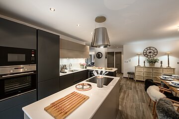 A kitchen with a clock on the wall above the stove