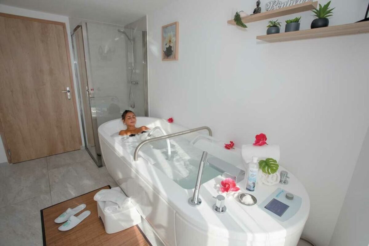 A woman is laying in a bathtub with a sign above her that says 