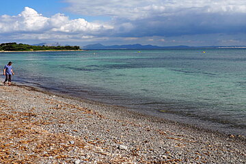two people walking on a pebble beach