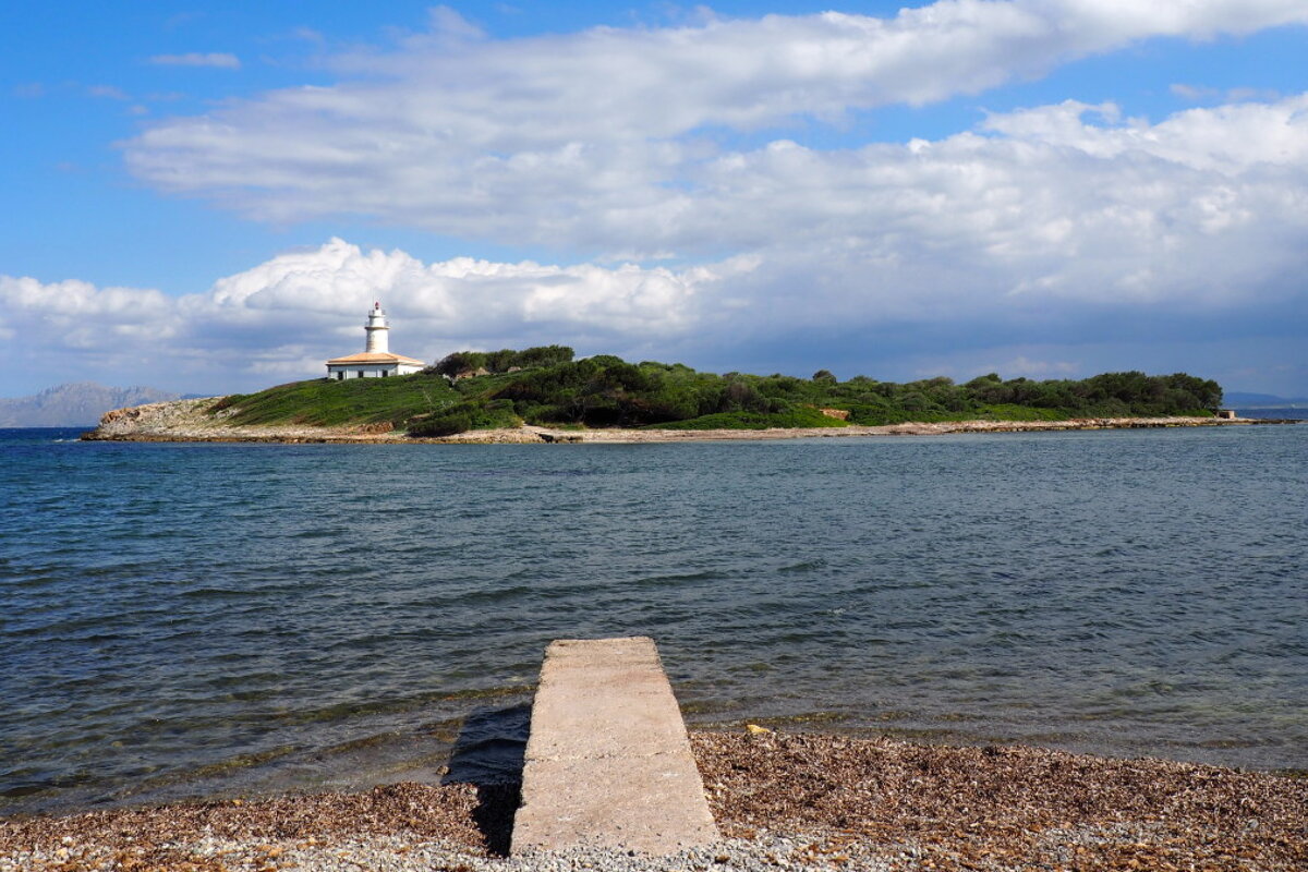 a jetty pointing towards an island off mallorca
