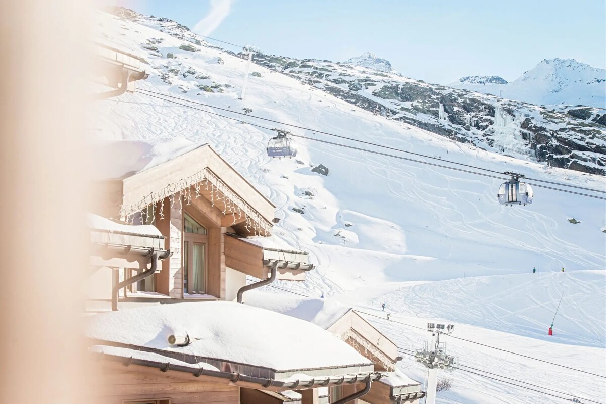 A ski lift is going down a snowy mountain