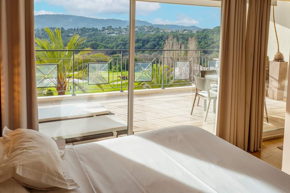 A bedroom with a view of a balcony and mountains