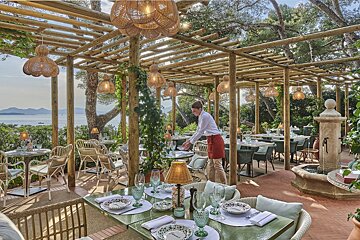 A man in a red apron is setting a table in a restaurant