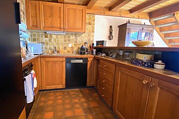 A kitchen with wooden cabinets and a black dishwasher