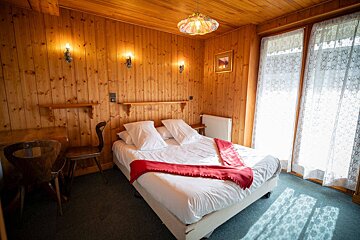 A bedroom with wood paneling and a bed with a red blanket on it
