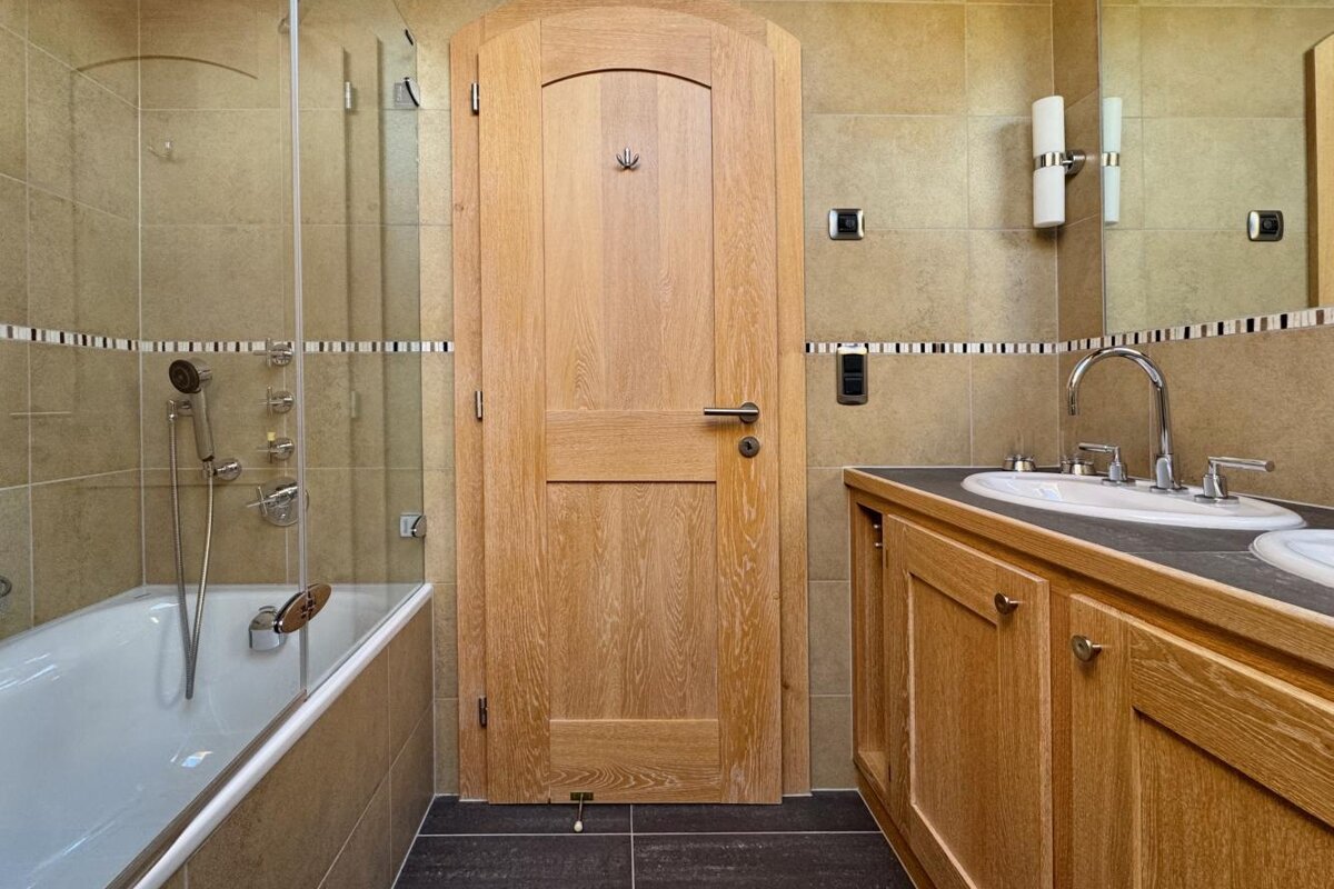 A bathroom with a wooden door and a bathtub