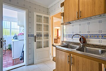 A kitchen with a stainless steel sink and wooden cabinets