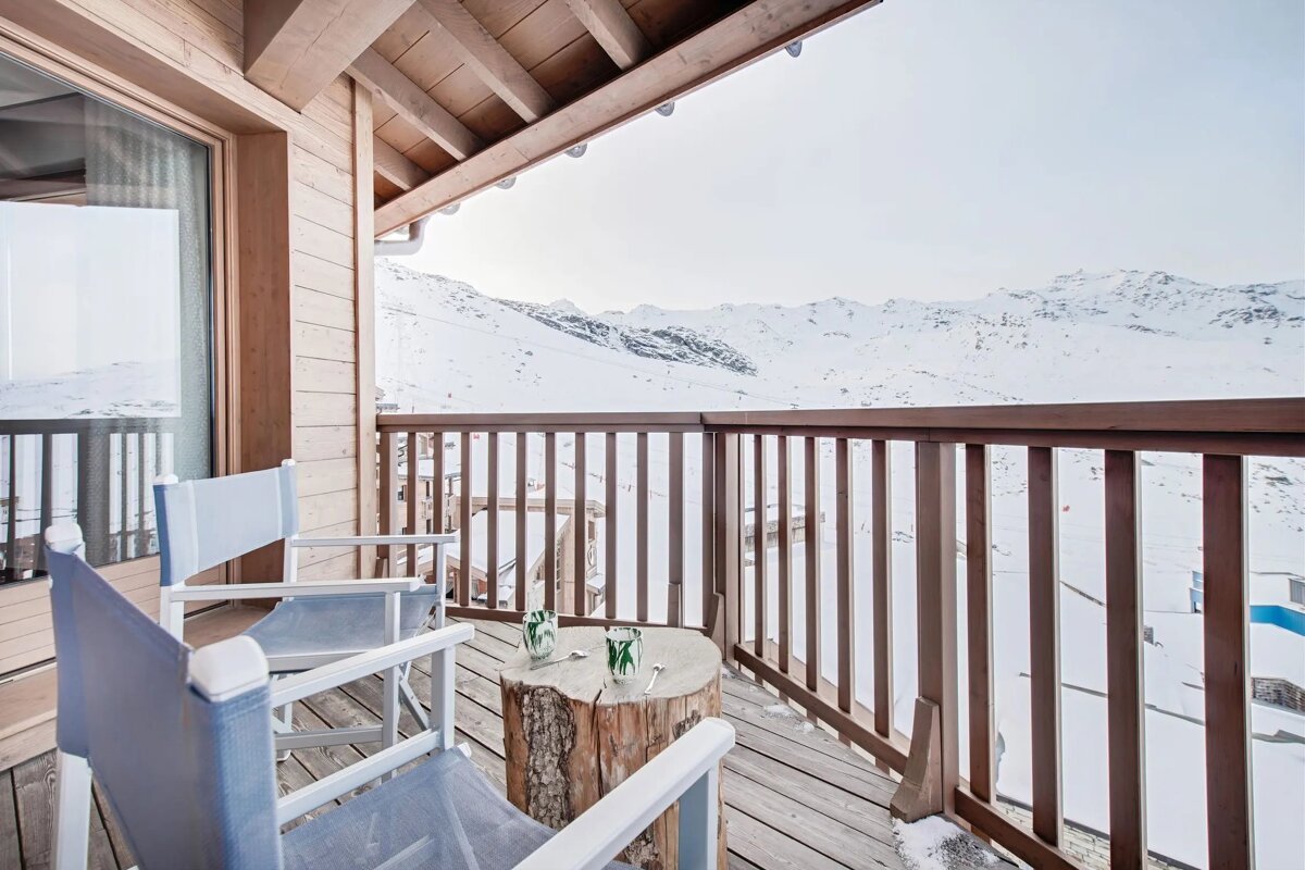 A balcony with two chairs and a table with glasses on it