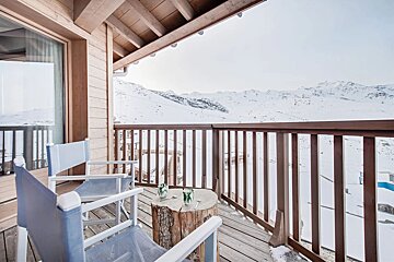 A balcony with two chairs and a table with glasses on it