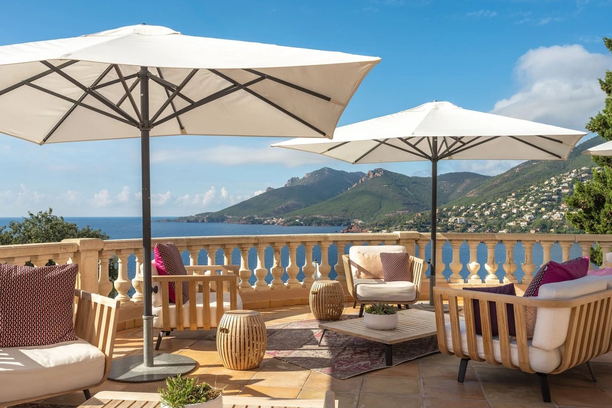 A balcony with chairs and umbrellas overlooking the ocean