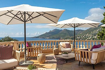A balcony with chairs and umbrellas overlooking the ocean