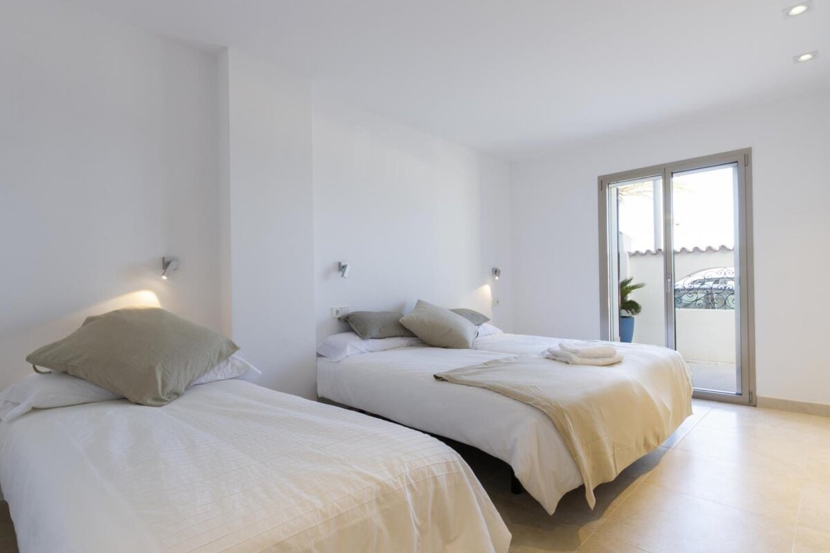 A bedroom with two beds and a sliding glass door