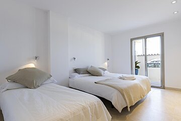 A bedroom with two beds and a sliding glass door