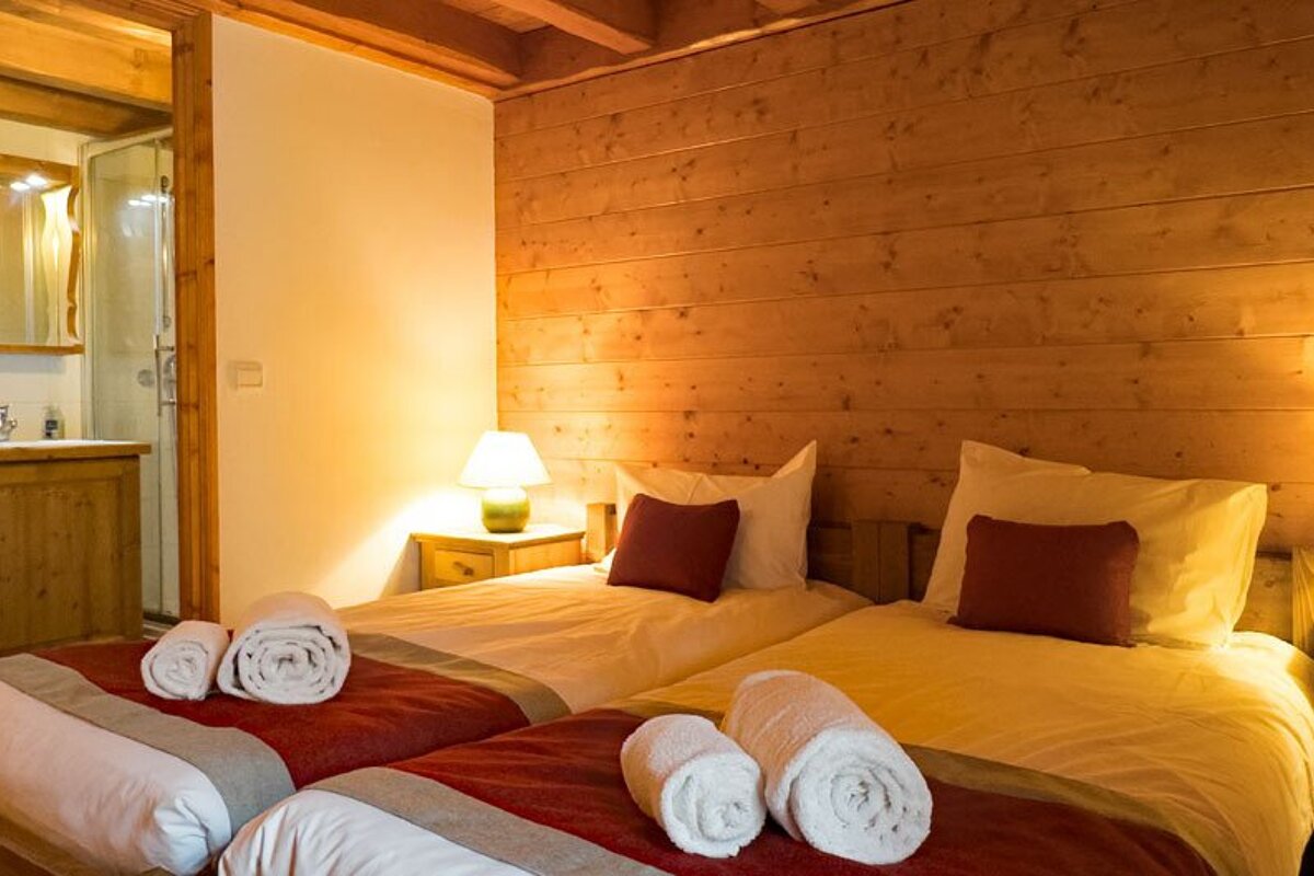 A bedroom with two beds and two lamps
