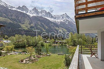 A balcony overlooking a lake with mountains in the background and the word ten80 on the bottom