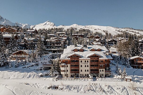 An aerial view of a snow covered ski resort with a large white building in the foreground