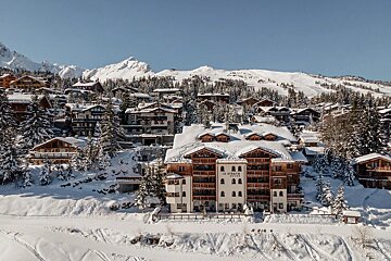 An aerial view of a snow covered ski resort with a large white building in the foreground