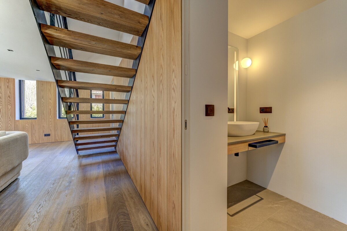 A wooden staircase leads to a bathroom with a sink