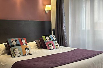 A bed with a purple blanket and colorful pillows on it