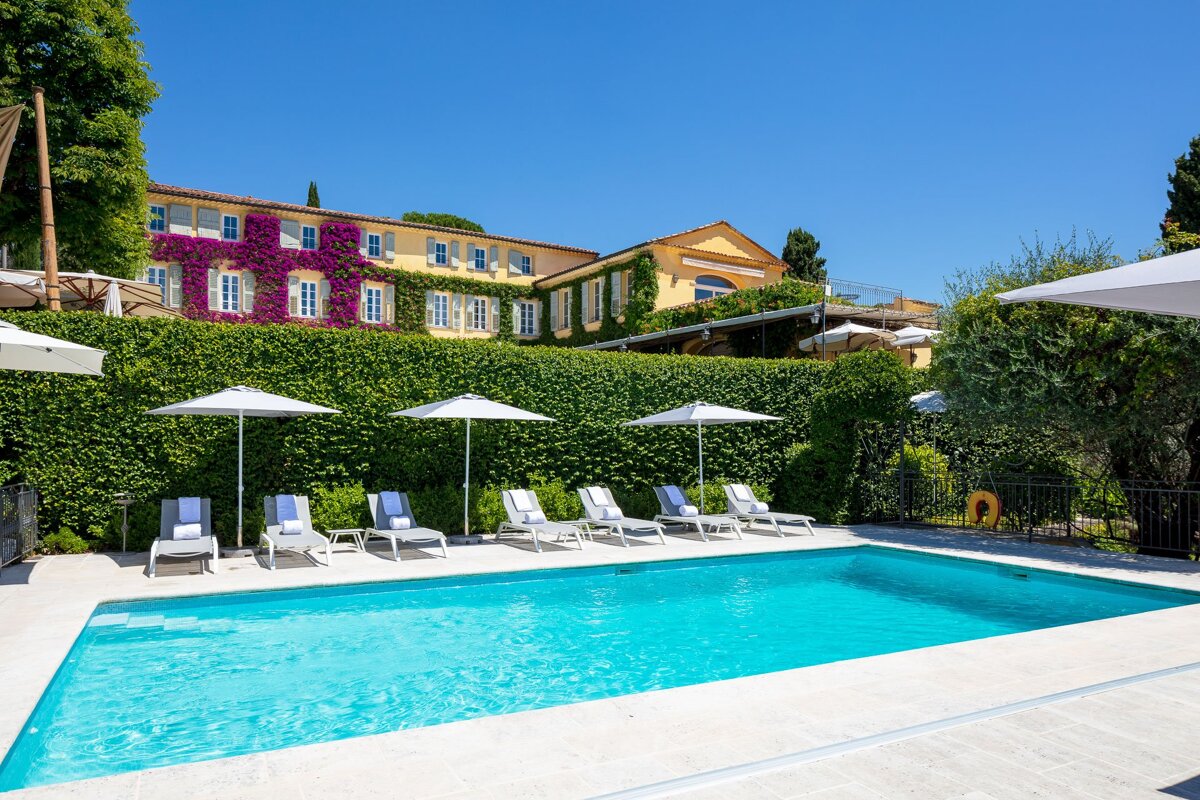 A large swimming pool surrounded by chairs and umbrellas
