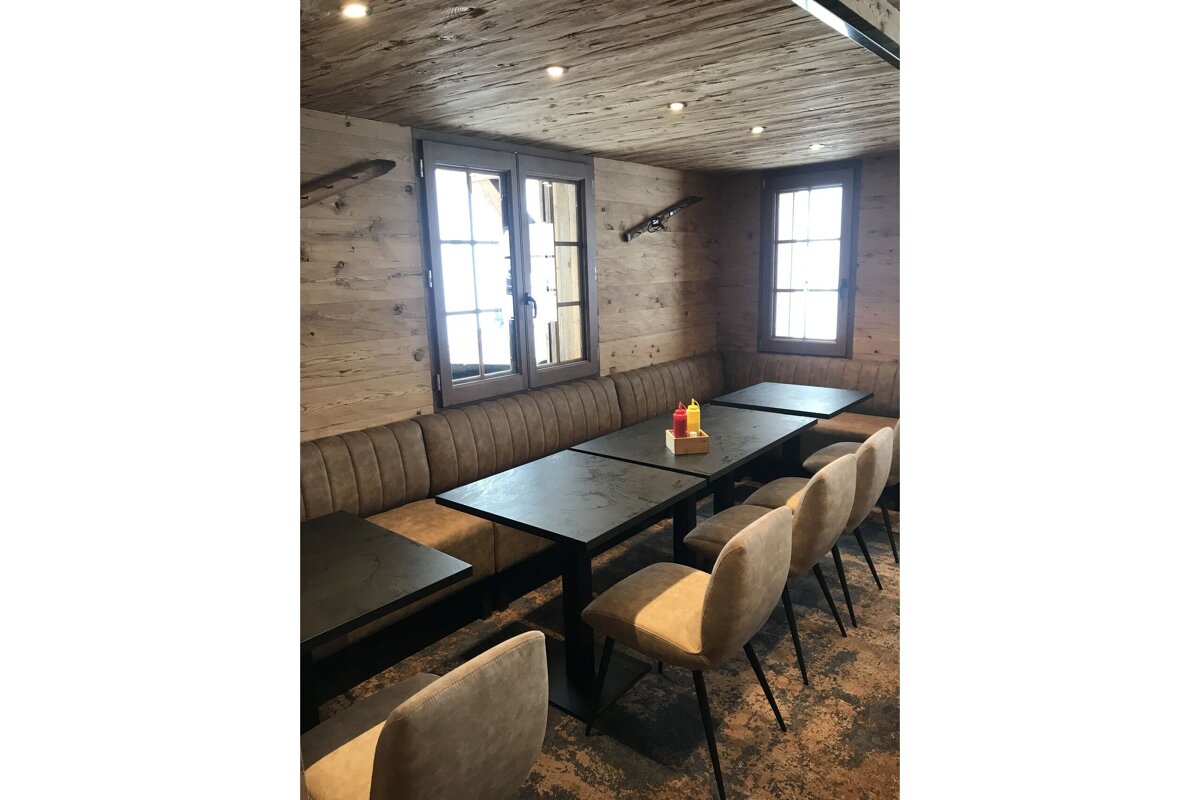 A row of tables and chairs in a room with a wooden ceiling