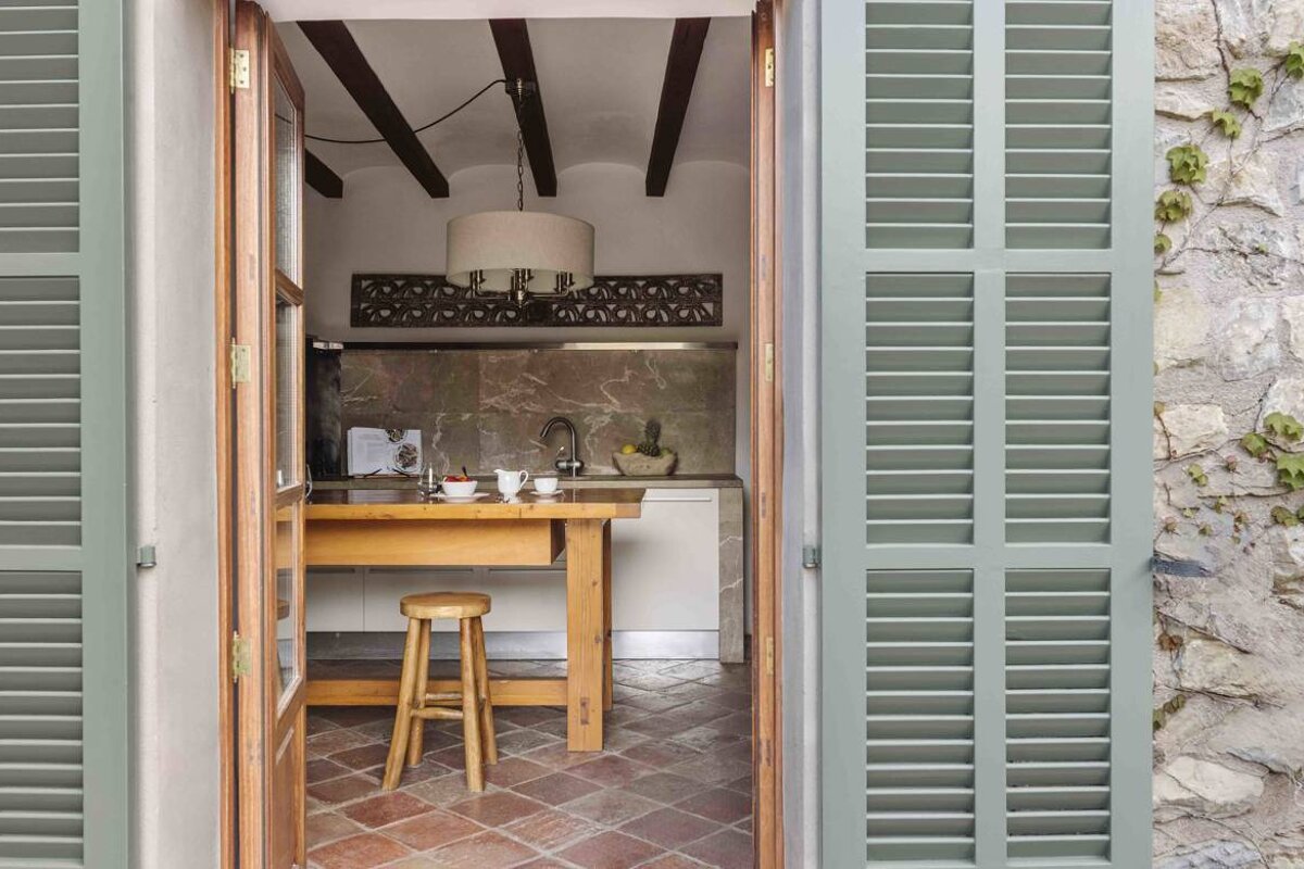 A kitchen with green shutters and a wooden table