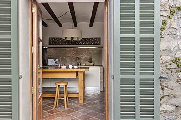 A kitchen with green shutters and a wooden table