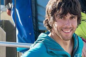 A man in a blue hoodie is smiling for the camera