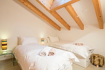 A bedroom with two beds and wooden beams on the ceiling
