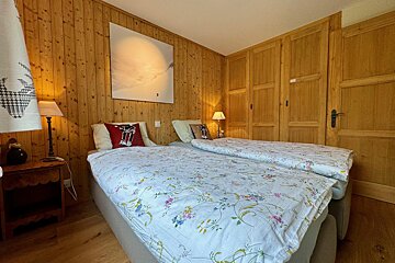 A bedroom with two beds and a painting on the wall