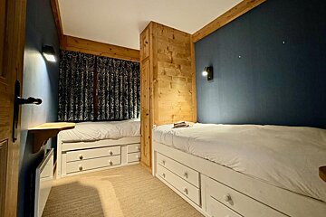 A bedroom with two beds and a blue wall
