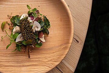 A wooden plate with a salad on it