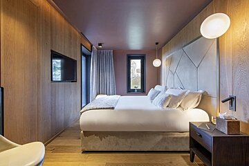 A bedroom with a large bed and a television on the wall
