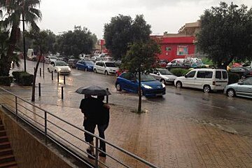 A couple is walking in the rain with an umbrella