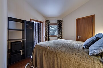 A bedroom with a bed and a wardrobe with boxes on the shelves