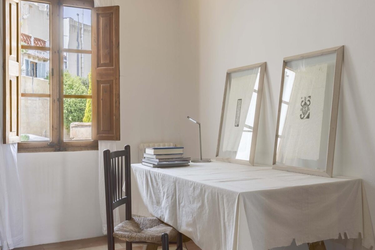 A stack of books sits on a table in front of a window
