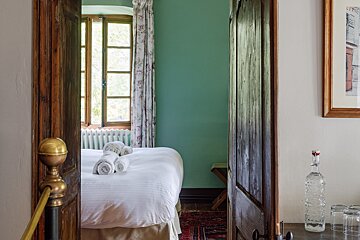 A bedroom with green walls and a bed with white sheets