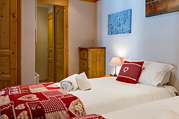A bedroom with two beds and a painting on the wall