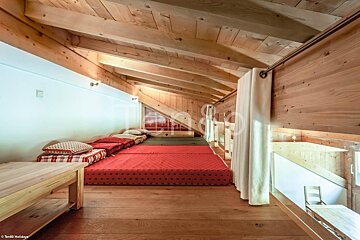 A wooden room with a red mattress and a white curtain